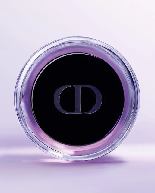 Close-up of a clear glass container with a black lid and the 'CD' logo, set against a soft lavender background, emphasizing beauty and luxury.