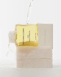 Costa Brazil Kaya Jungle Firming Oil bottle resting on a white stone block with water splashing over it