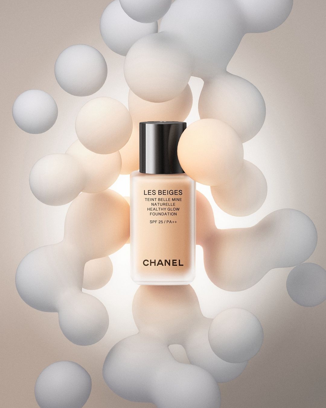 Chanel Les Beiges foundation product shot. Cosmetic product in a transparent container is centered among abstract floating spheres.