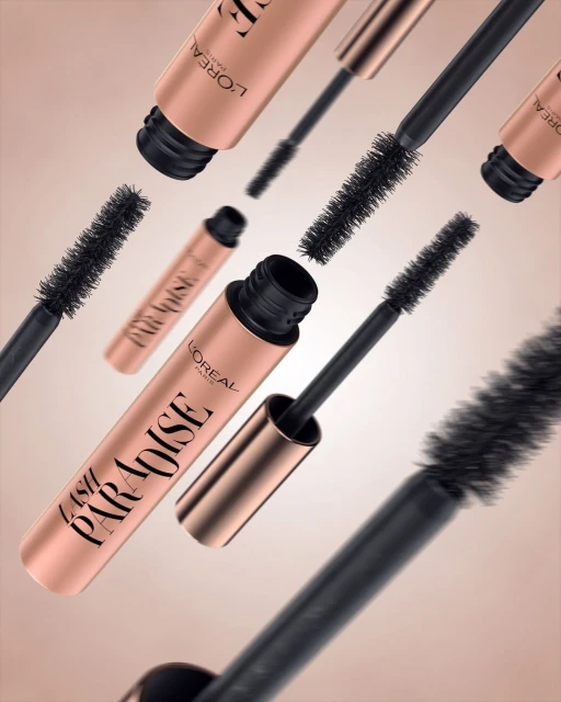 Multiple tubes of L'Oreal Lash Paradise mascara with black wand applicators floating on a neutral background in a beauty product still life.