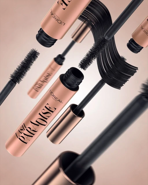 Still life shot of L'Oreal Lash Paradise mascara tubes and wands floating against a pale pink backdrop, showcasing the product.