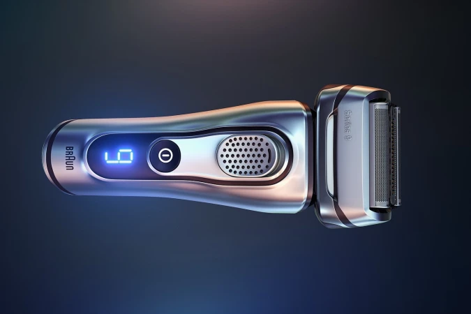 Shiny silver electric shaver on dark blue background featuring a digital display and sleek design; beauty and personal care product.