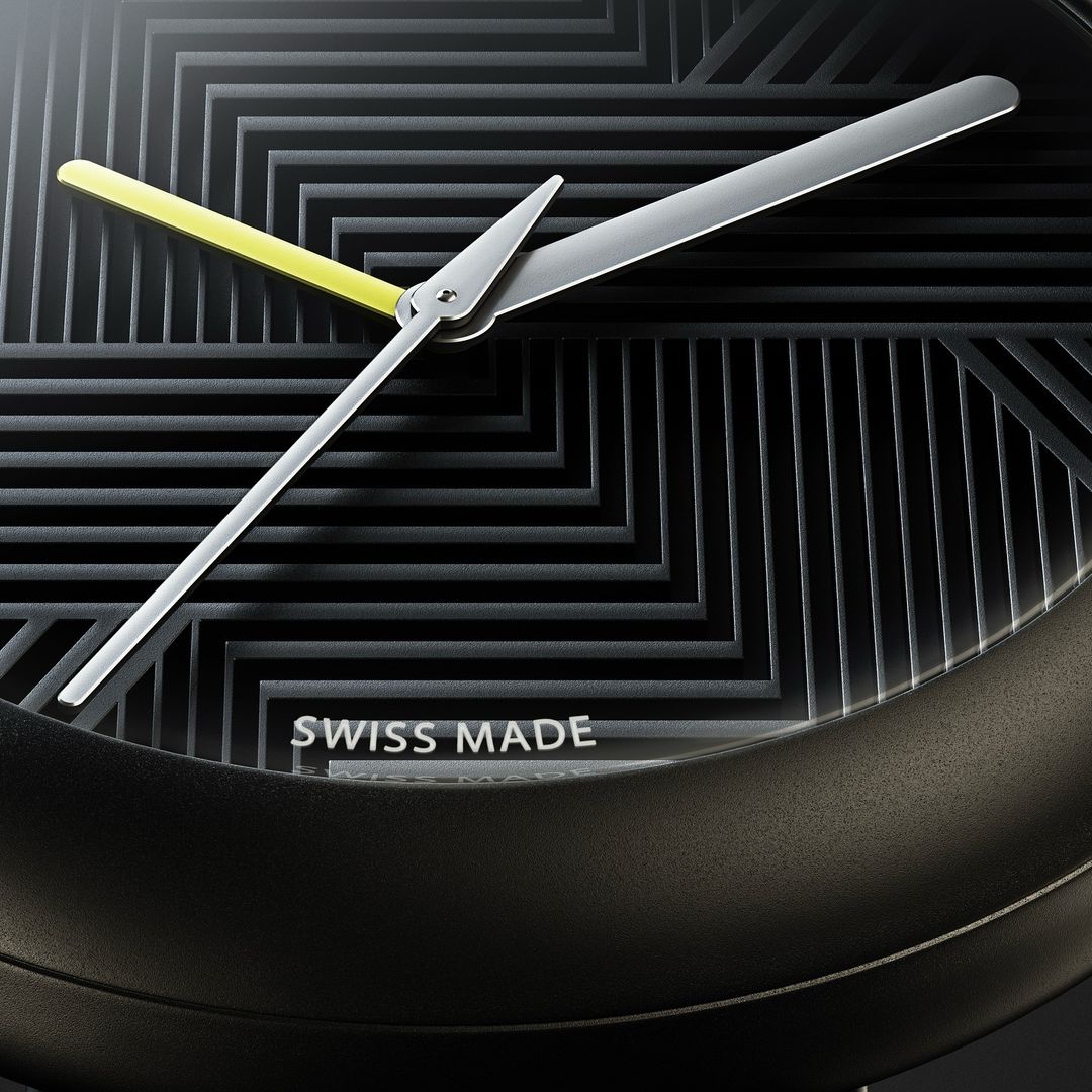 Close-up of a black and gray watch face with yellow second hand and silver minute and hour hands against a geometric dial.