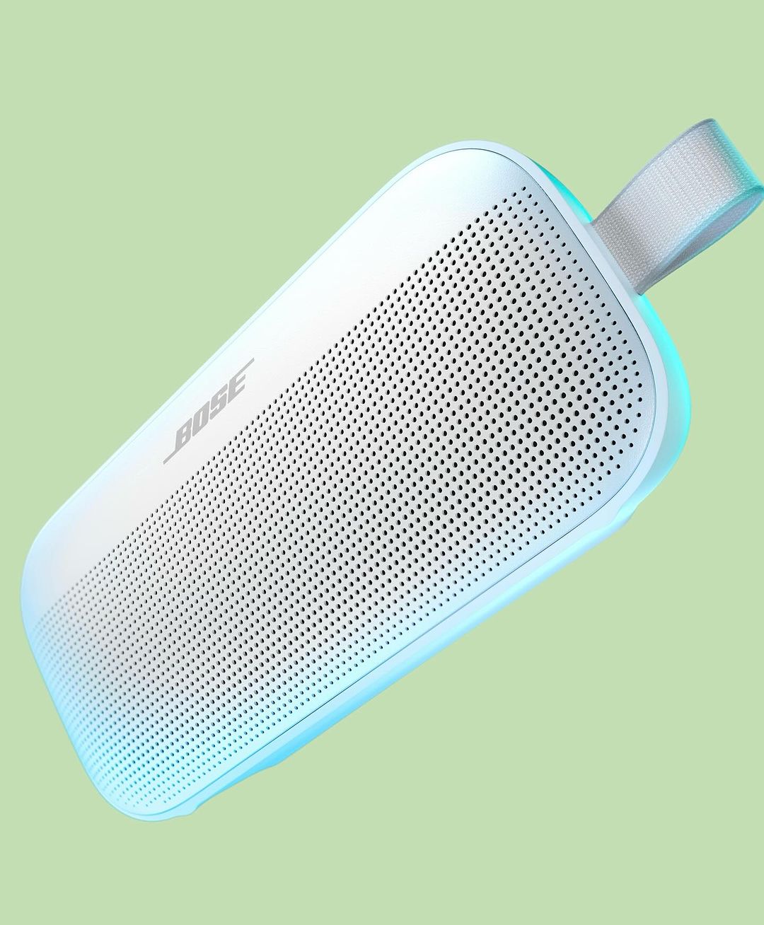 White Bose speaker isolated on green background. Portable audio device with fabric handle, wireless connectivity, and minimalist design.