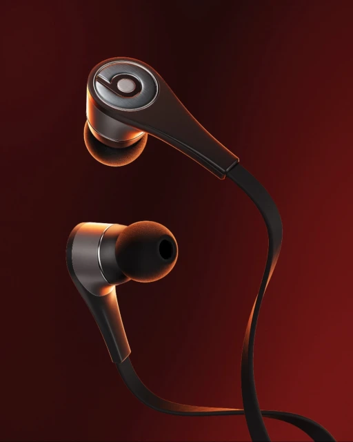 Close-up studio shot of black Beats in-ear headphones with silver accents against a blurred gradient red-orange background. Product photography.