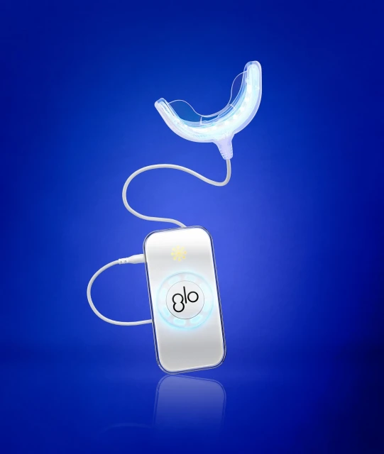 Dental teeth-whitening system with mouthpiece and handheld control device on a gradient blue background, promoting oral healthcare.