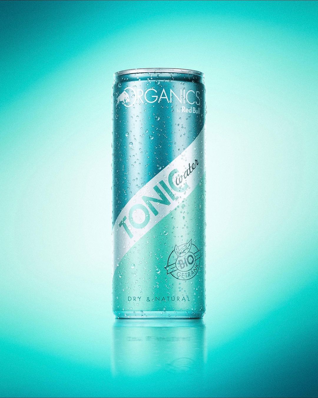 A teal can of Organics by Red Bull Tonic Water with water droplets, showcased against a gradient blue background for a product shot.