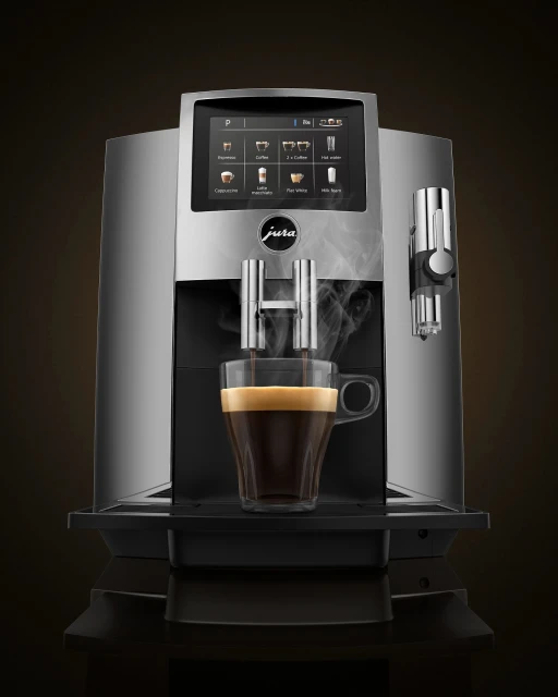 Jura coffee machine dispensing espresso into a clear glass cup, with steam rising, set against a gradient brown backdrop.