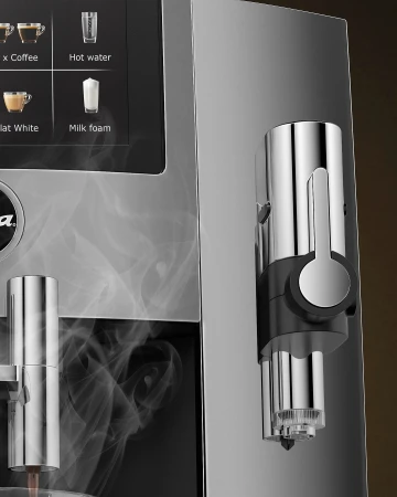 Close-up of a modern, chrome-plated coffee machine with a digital display and steam rising, highlighting its sleek design and functionality.