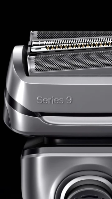 Close-up of a silver Braun Series 9 electric razor head featuring multiple cutting elements and a textured surface against a black backdrop.