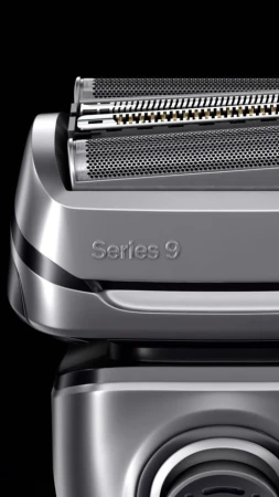 Close-up of a silver Braun Series 9 electric razor head featuring multiple cutting elements and a textured surface against a black backdrop.