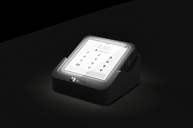 A digital payment terminal displays a keypad and a monetary value of 7.50 against a dark, shadowy background in a studio product shot.