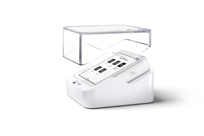 White electronic device with a screen displaying icons under a clear plastic cover on a white background, studio lighting.
