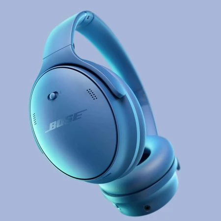Close-up of blue Bose QuietComfort headphones on a blue background with studio lighting, showcasing its design and audio technology.