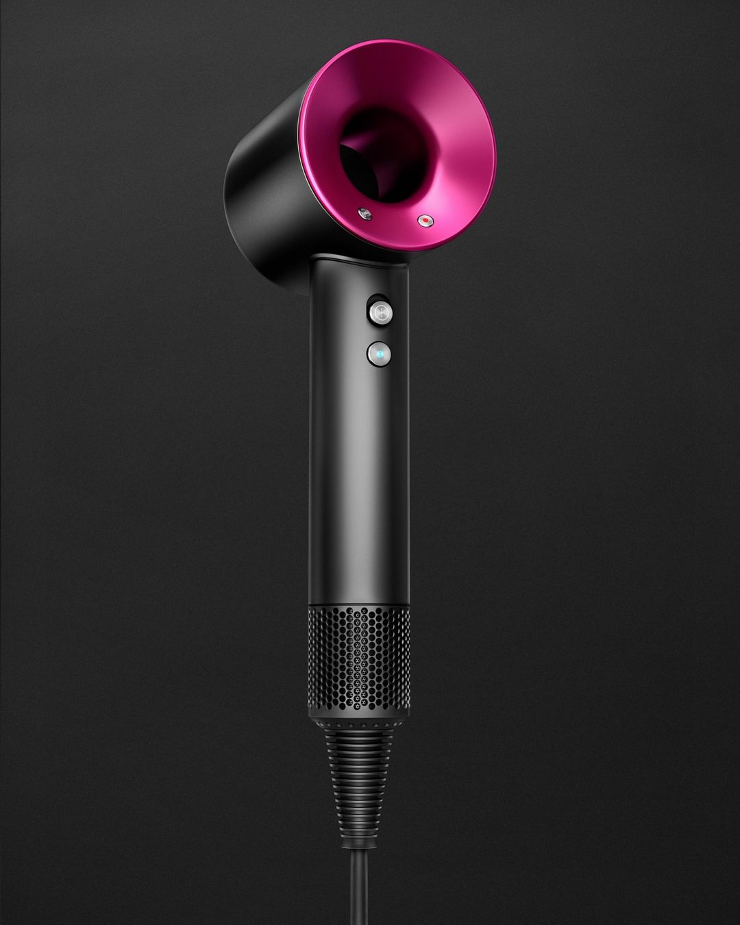 Close-up of a sleek, dark gray Dyson hair dryer with a vibrant pink nozzle against a dark gray backdrop, highlighting modern design.