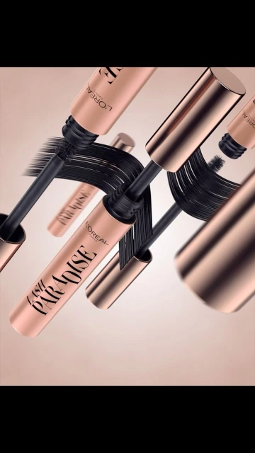 L'Oreal Paris Paradise mascara tubes with applicators floating against a tan background in a beauty product shot.