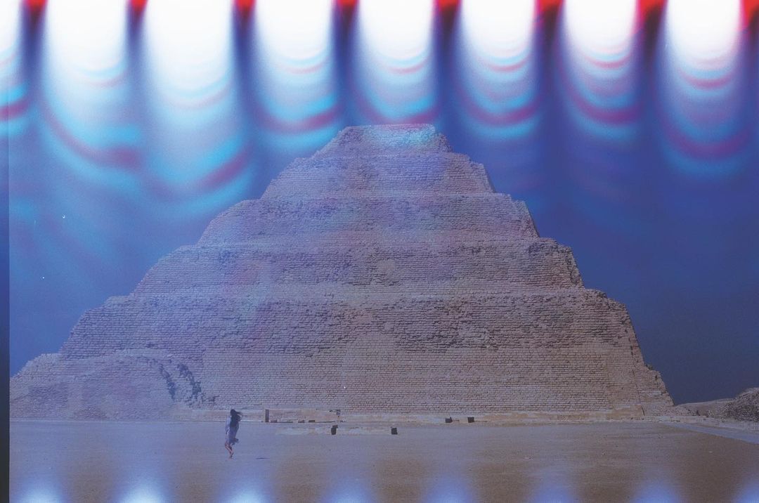 Stepped pyramid, possibly in Egypt, captured on film with a long exposure effect and a solitary person walking in the foreground.
