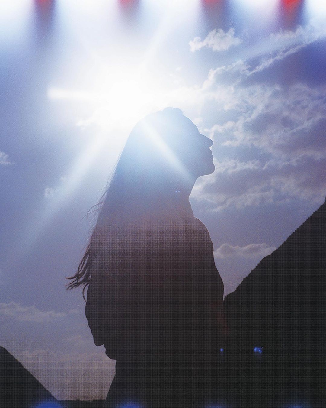 Silhouette of a woman looking up at the sky with the sun shining behind her near the Egyptian pyramids. Outdoor shot.
