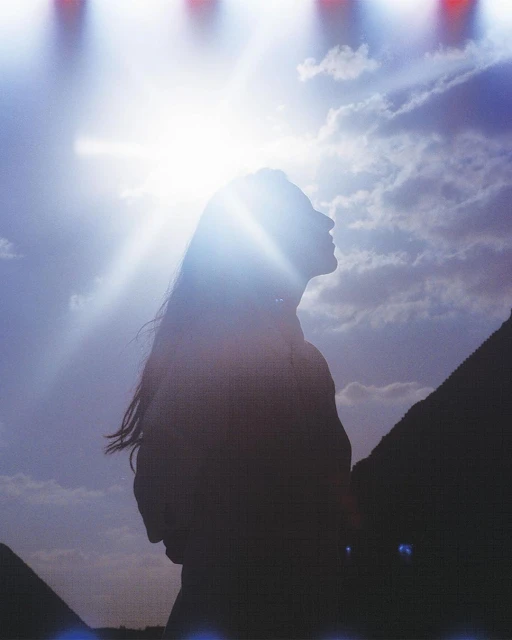 Silhouette of a woman looking up at the sky with the sun shining behind her near the Egyptian pyramids. Outdoor shot.