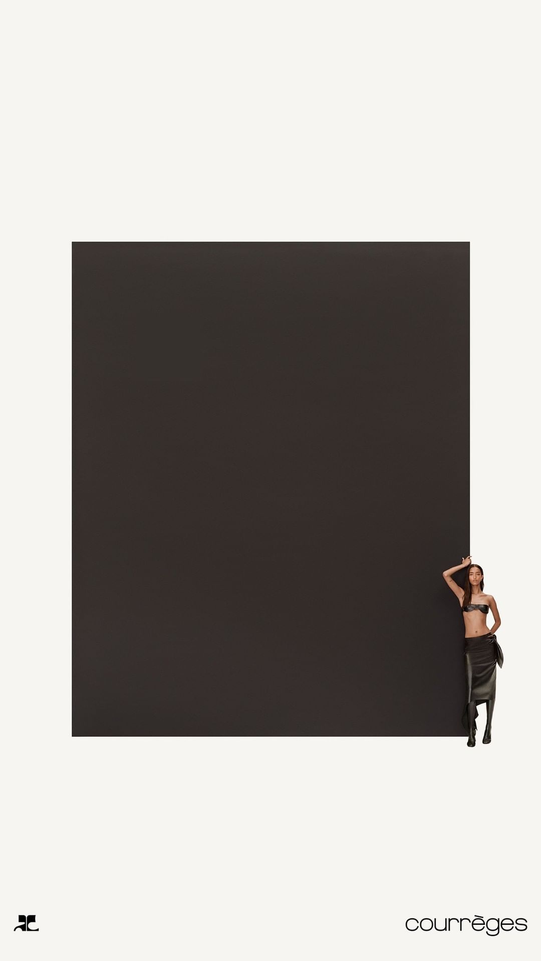Woman in a black two-piece outfit poses next to a large black square, minimalist fashion shot, against a cream-colored background.