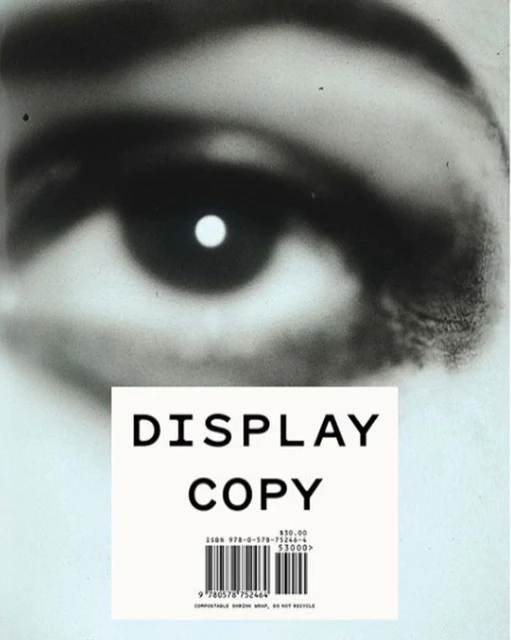 Close-up of an eye in black and white, contrasted against a label with the words 'DISPLAY COPY' printed in bold letters.
