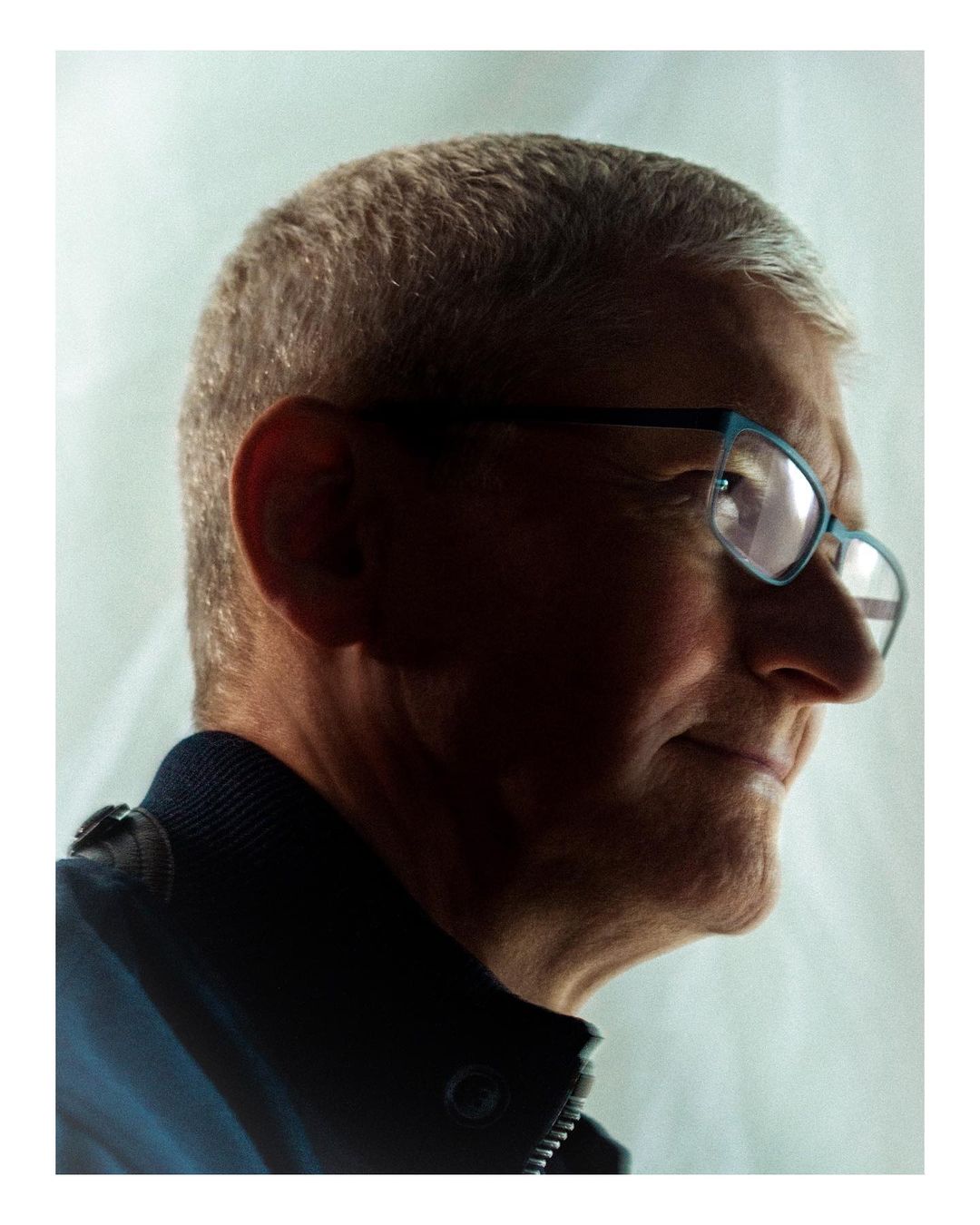 Portrait of an adult male wearing glasses, captured in a close-up side shot with a light background, showcasing a blend of shadows.
