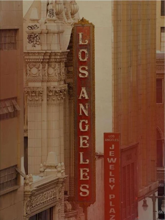 Vertical exterior photograph featuring a vintage red Los Angeles theater sign mounted on a historic architectural building