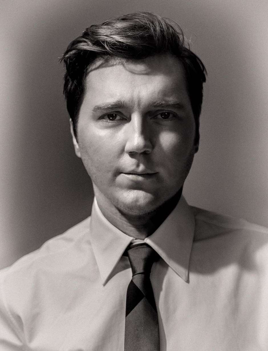 Portrait of adult male with a serious expression wearing a white shirt and tie against a neutral background in a photo studio setting.
