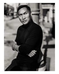 Monochrome portrait of a man in a black turtleneck leaning against a column outdoors in New York by Mark Mahaney.