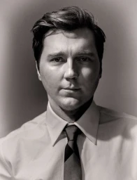 Portrait of actor Paul Dano in a collared shirt and tie, shot in monochrome with soft directional lighting.