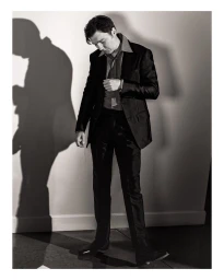 Man in dark suit and dress shirt standing against a wall with a prominent shadow, photographed by Mark Mahaney.