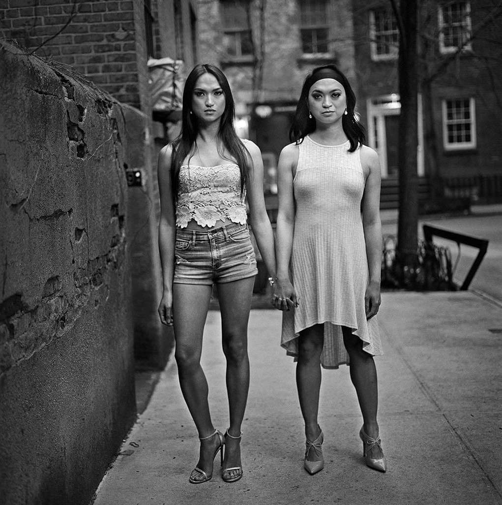 Two women holding hands standing on a city sidewalk in a black and white portrait by Mark Seliger in New York.