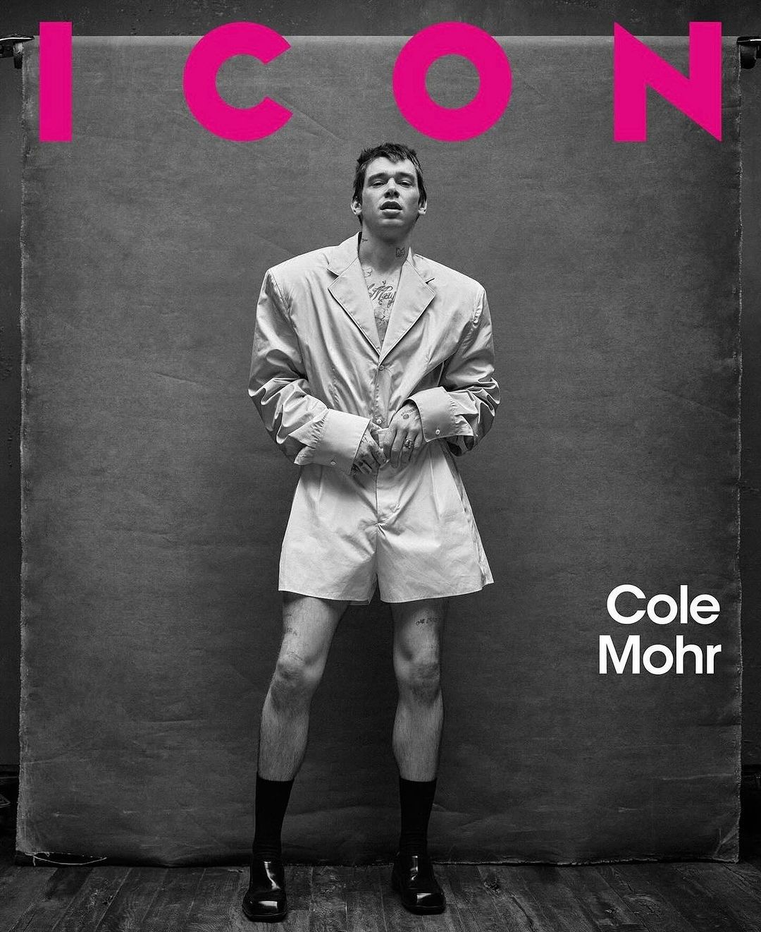 Monochrome portrait of Cole Mohr, an adult male, posing in a light jacket and shorts, standing against a textured backdrop. Text overlay.