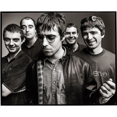 Black and white portrait of the band Oasis, featuring five members in a close-up studio shot, showcasing their individual styles and expressions.