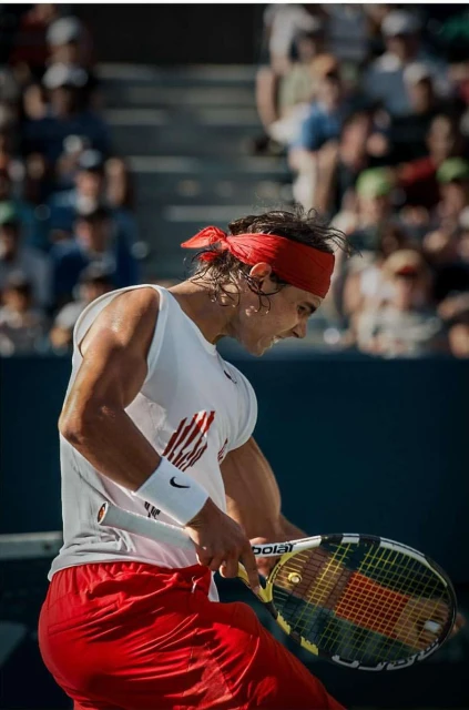 Professional tennis player with red headband in action on outdoor tennis court, focused and determined during a match.