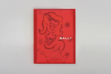 Red rectangular book cover featuring a stamped illustration of a mermaid figure and the brand text Bally.