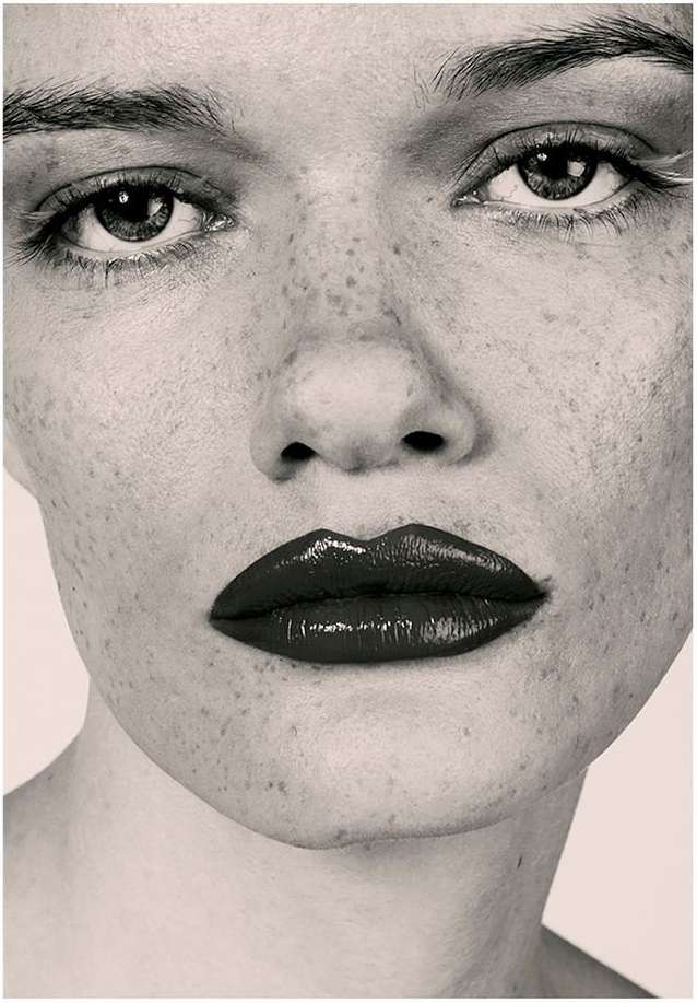 Extreme close up portrait of a woman with heavy freckles and dark glossy lipstick photographed by Marta Bevacqua