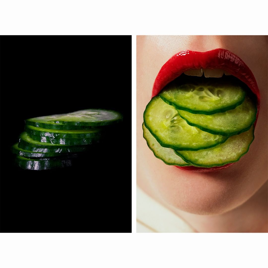 Close-up of a woman's red lips with cucumber slices, split from a stack of fresh cucumber slices against a black background.