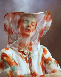 Model wearing a white and orange patterned hooded veil covering her face, photographed by Marta Bevacqua.