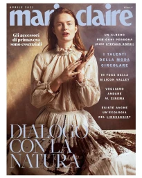 Magazine cover featuring a red-haired woman in a high-collared cream ruffled blouse against a textured backdrop by Marta Bevacqua