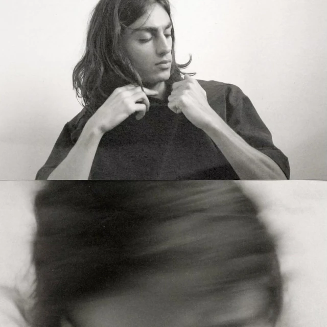 Black and white portrait of a young adult with long hair wearing a dark shirt, captured with a unique blurred effect below.