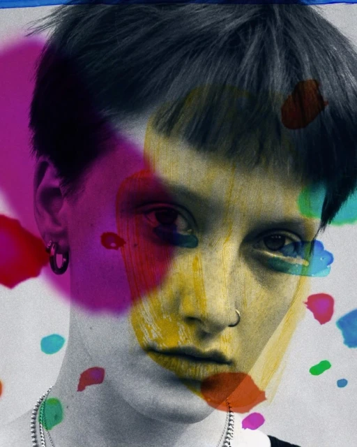 Close-up portrait of a person with short dark hair and a nose ring, overlaid with abstract colorful paint splashes in pink, yellow, blue, and green.