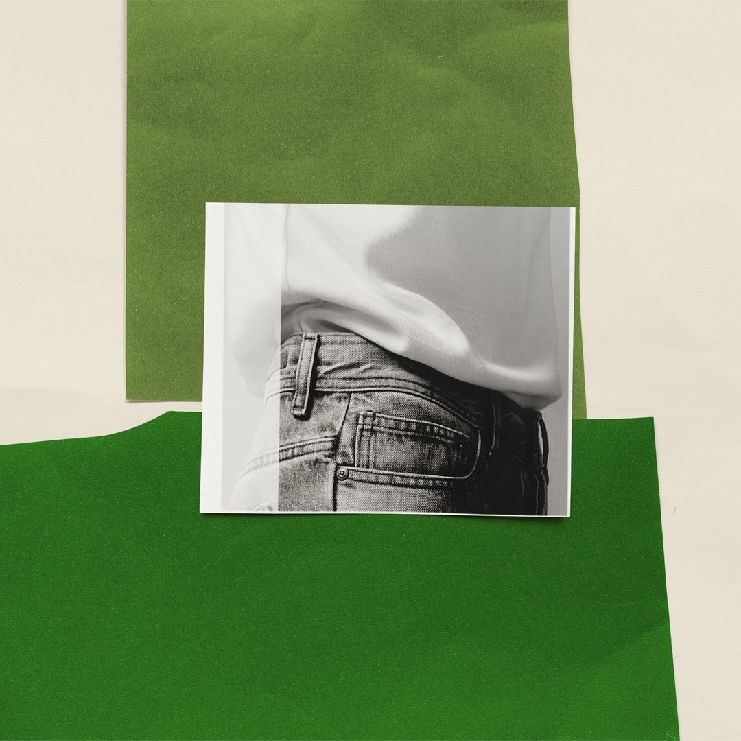 Cropped monochrome photograph on paper depicts person in jeans with white top, displayed against cream and green paper background.