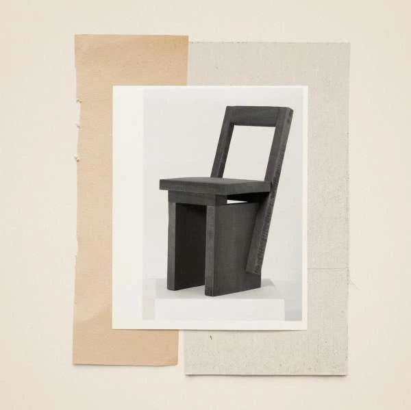A grey chair in a collage-style composition. The chair is set against a background of beige, white, and grey paper textures.