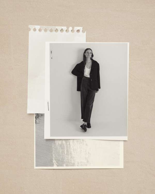 Black and white portrait of a young woman in a black jacket and dark trousers on a photo print, placed on craft paper.