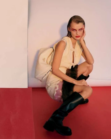 Model wearing a cream dress and black boots crouching against a studio backdrop, by illustrator Martin Cole.