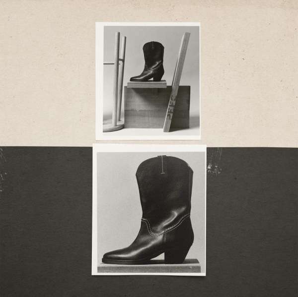 Black and white photographic studio still life featuring a cowboy boot placed in the center of two square photos.