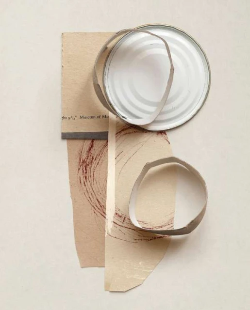 Abstract collage art featuring paper scraps, concentric circles, and a white tin can lid against a neutral background.