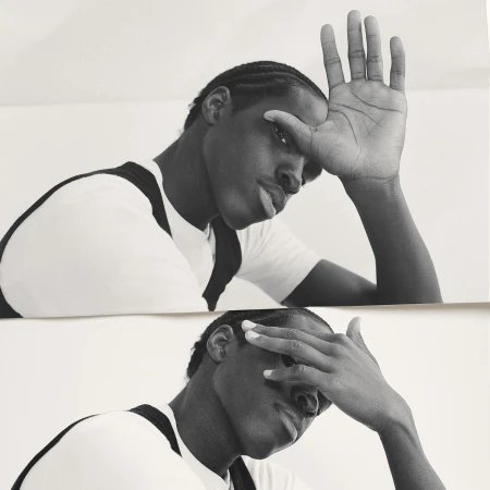 Black and white portrait of a black man with cornrows, partially covering his face with his hand in a reflective double exposure.