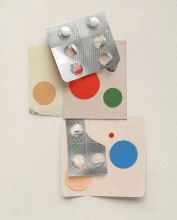 Blister packs with pills on top of colorful square paper with round stickers. Healthcare and pharmaceutical products concept in studio light.